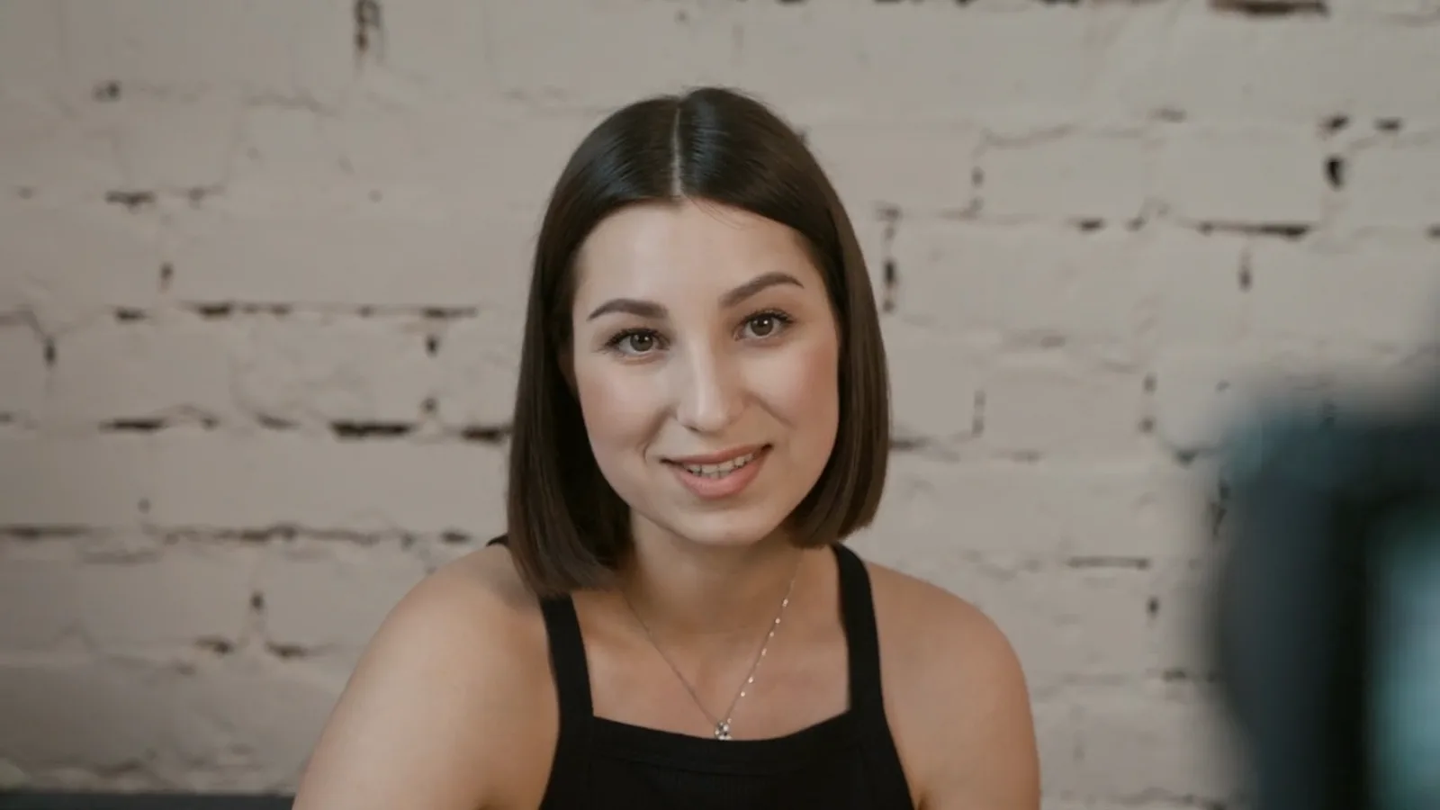 A speaker filmed against a white brick wall, before background removal